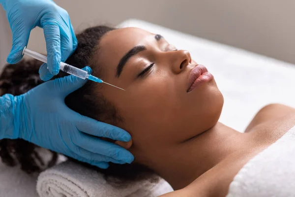 Jeune femme noire recevant une injection de la zone des yeux au salon de beauté — Photo