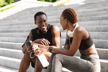 Sportif siyah adam ve kadın spor salonundan sonra birlikte dinleniyorlar.
