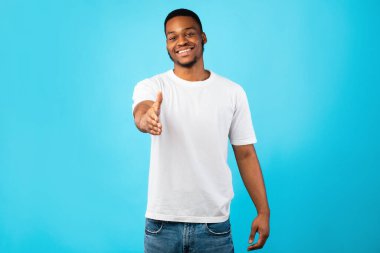 Mavi Stüdyo Arkaplanı Üzerinde El sıkışmak için Siyah Adam Uzatıyor
