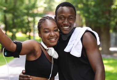 Açık havada antrenmandan sonra sevgilisiyle selfie çeken mutlu siyah kız.