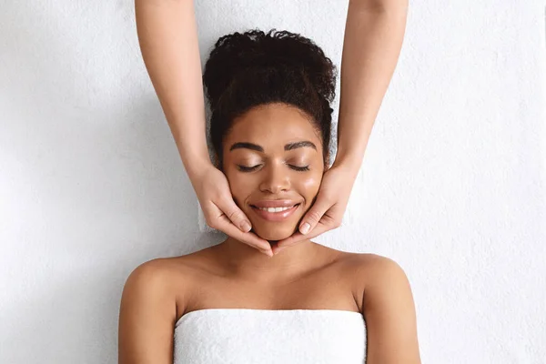 Terapeuta fazendo levantamento massagem facial para bela senhora negra — Fotografia de Stock