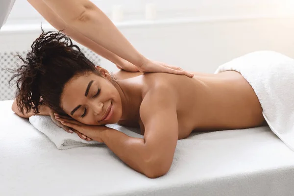 Zwarte jonge vrouw genieten van genezing terug massage in spa — Stockfoto