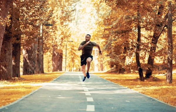 Тренировка черных спринтеров для бега по беговой дорожке в красивом осеннем парке, пространство для копирования — стоковое фото