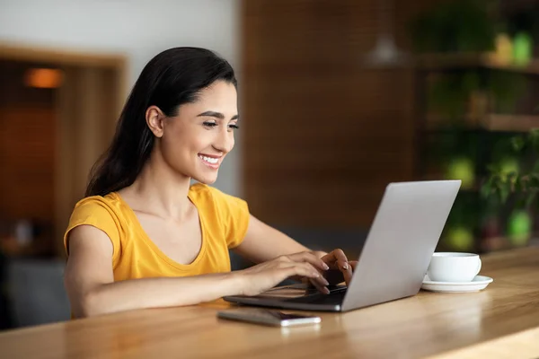 Smiling arab girl freelancer chatting with client, cafe interior