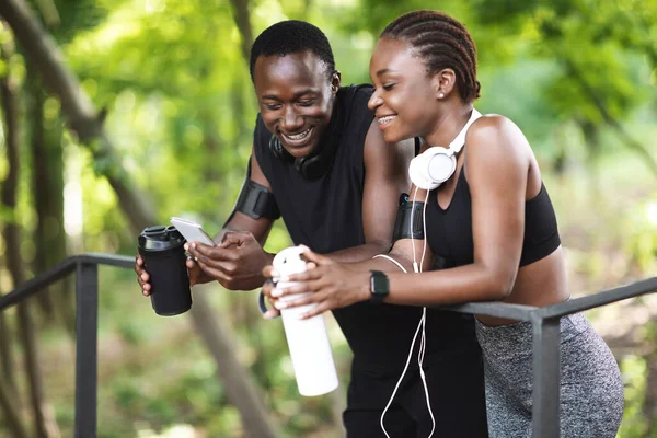 Casal Africano descansando depois de trabalhar fora ao ar livre, usando Smartphone e água potável — Fotografia de Stock