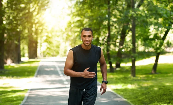 Mutlu Afrikalı Amerikalı koşucu güneşli bir günde şehir parkında koşuyor. — Stok fotoğraf