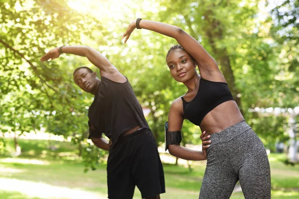 Formação ao ar livre. Casal negro atlético fazendo exercícios esportivos juntos no parque — Fotografia de Stock