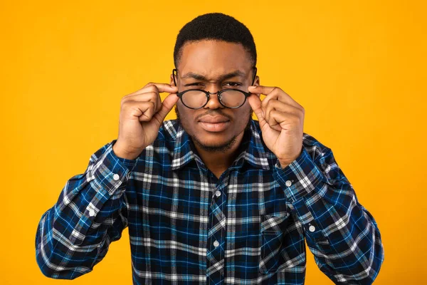 Homem em óculos olhando para a câmera Squinting Eyes, fundo amarelo — Fotografia de Stock