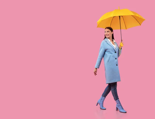 Портрет збудженої молодої жінки, що йде з жовтим парасолькою — стокове фото