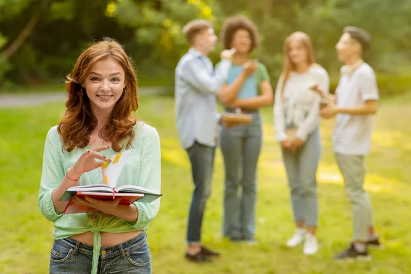 Retrato de estudiante universitaria sonriente con libros de trabajo posando al aire libre en el campus — Foto de Stock