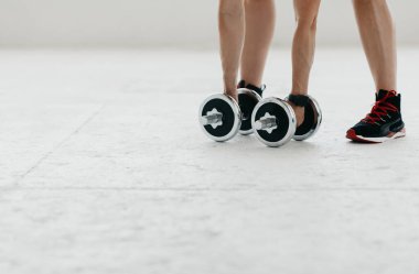 Sağlık ve güç eğitimi. Fitness takipçisi olan bir kadın el bükme ve halterle egzersiz yapıyor.