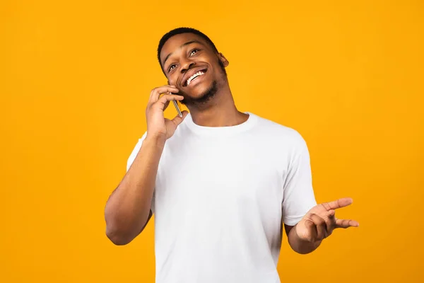 Positiv afrikansk man talar på mobiltelefon över gul bakgrund — Stockfoto