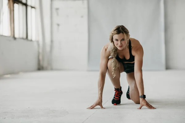 Entrena, corre y empieza. Mujer musculosa en ropa deportiva con rastreador de fitness haciendo ejercicio en el gimnasio —  Fotos de Stock