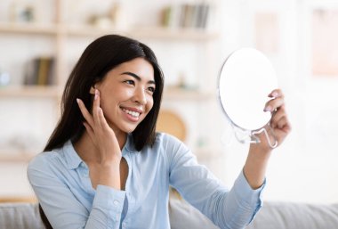 Doğal Güzellik. Asyalı kız büyüteç tutuyor ve kusursuz tenine dokunuyor.