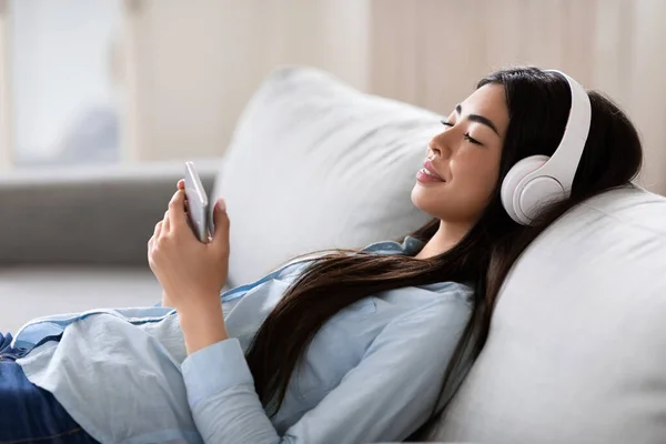 Aplicación Audio Books. Mujer Asiática Con Smartphone Y Auriculares Relajante En Casa — Foto de Stock