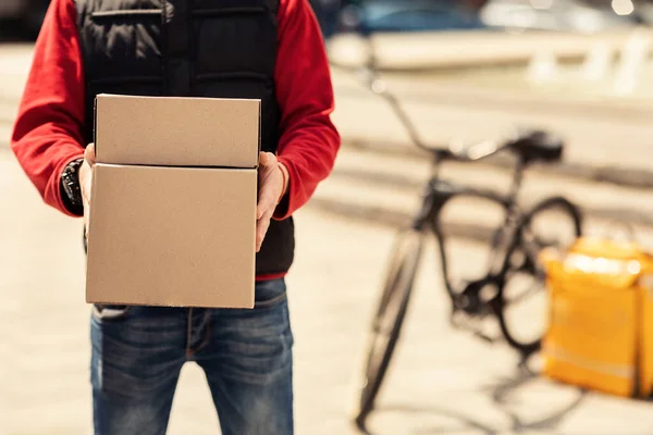 Entrega irreconhecível cara segurando caixas entregando comida na cidade, cortado — Fotografia de Stock