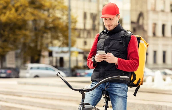Dostawca na rowerze przy użyciu telefonu odbieranie zamówienia żywności na zewnątrz — Zdjęcie stockowe