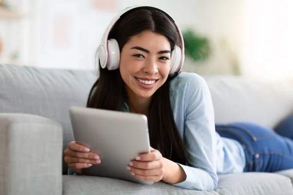 Tecnologías para el ocio. Chica coreana con tableta digital y auriculares en casa — Foto de Stock