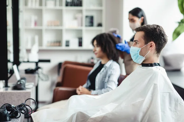 Man met medisch masker zittend aan kappers, wachtend op meester — Stockfoto