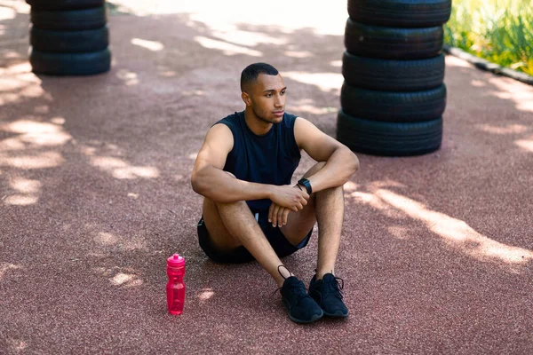 Milenial negro jogger tomando descanso de la formación en el parque en día soleado —  Fotos de Stock