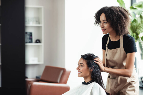 Young brunette enjoying beauty procedures at hairdresser salon