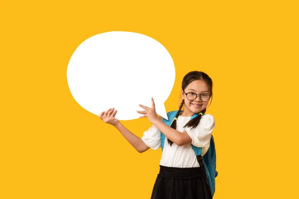 Menina da escola asiática feliz que prende a bolha da fala que está no estúdio — Fotografia de Stock