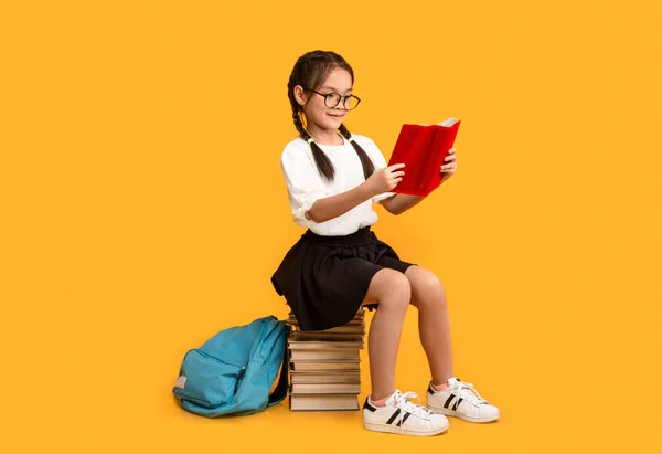 Allegro asiatico studentessa lettura seduta su libro stack in studio — Foto Stock