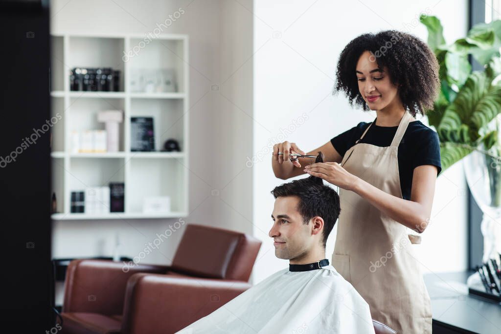 Cheerful guy getting new haircut at hairdressers, empty space