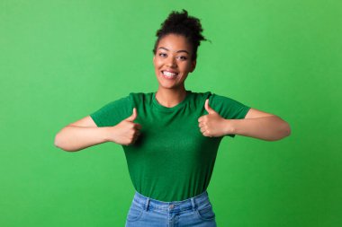 Afro kadın baş parmağını gösteriyor ve gülümsüyor.