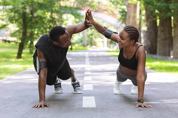 Casal preto motivado dando high-five um ao outro enquanto trabalhava ao ar livre — Fotografia de Stock