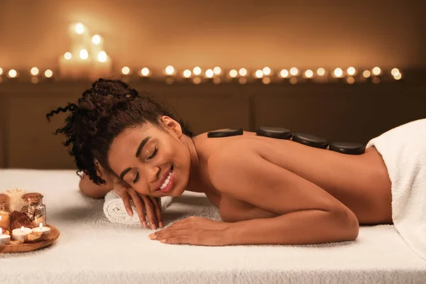 Black young woman getting hot stone massage at spa — Stock Photo, Image