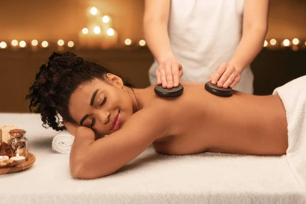 Terapeuta de spa fazendo massagem profissional de pedra quente — Fotografia de Stock