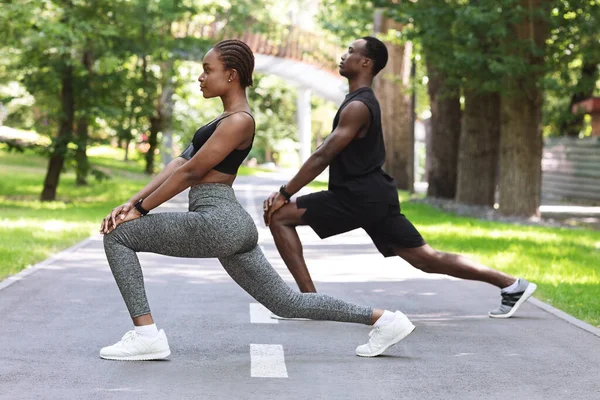 Estilo de vida desportivo. Casal de fitness preto trabalhando juntos no parque, alongamento músculos — Fotografia de Stock