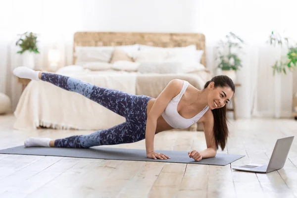 Entrenamiento en línea. Asiática chica haciendo deportes en frente de portátil en casa — Foto de Stock