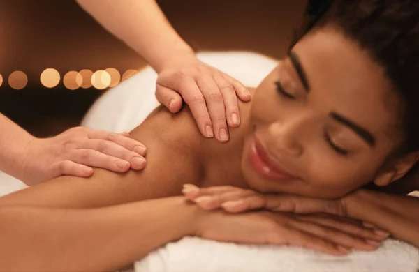 Therapist rubbing relaxed black woman shoulders, closeup — Stock Photo, Image