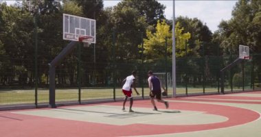Çeşitli basketbol oyuncuları bir sokak topu maçında pratik yapıyor.