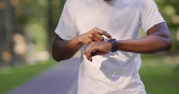 Zwarte man controleert zijn activiteit status op smartwatch tijdens het lopen — Stockfoto