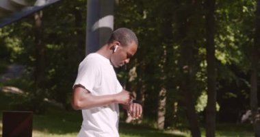 Kulaklık takmış Afro-Amerikalı adam akıllı adam hareketlerini kontrol ediyor.
