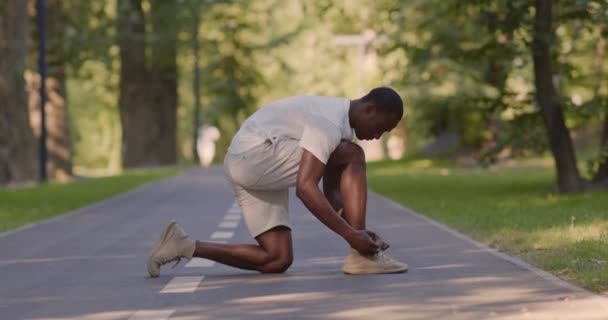 Černý sportovec vázání tkaničky na běžecké dráze — Stock video