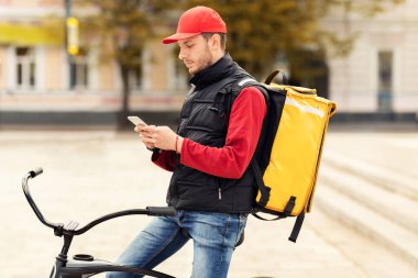 Akıllı Telefondaki Kurye Mesajlaşması Bisikletin üzerinde oturuyor Dışarıda öğle yemeği dağıtıyor