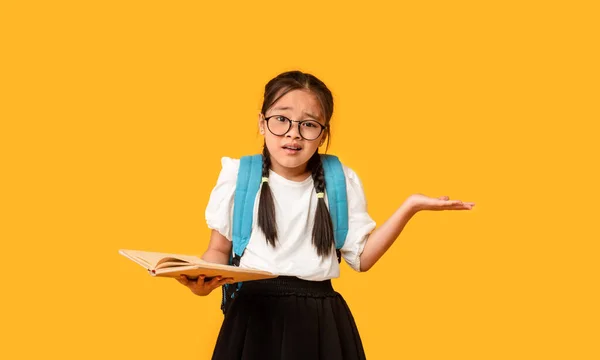 Confused Korean Schoolgirl Holding Book Shrugging Shoulders Over Yellow Background — Stock Photo, Image