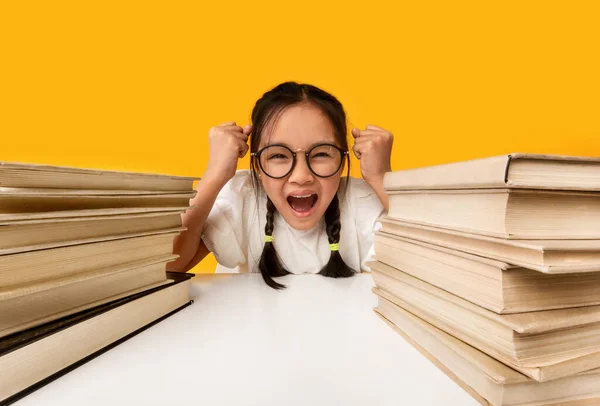 Ασιάτισσα μαθήτρια φωνάζει κλαίγοντας καθισμένη στα σχολικά βιβλία, κίτρινο φόντο — Φωτογραφία Αρχείου