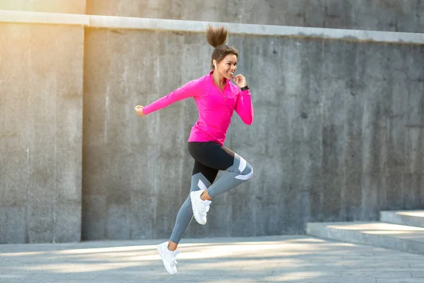 Mujer africana alegre en ropa deportiva saltando al aire libre — Foto de Stock