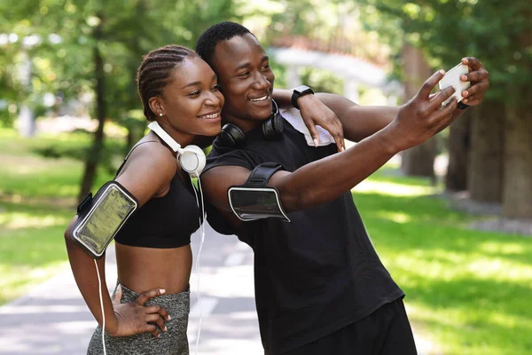 Sporty casal preto tomando selfie no smartphone durante a pausa no treinamento ao ar livre — Fotografia de Stock
