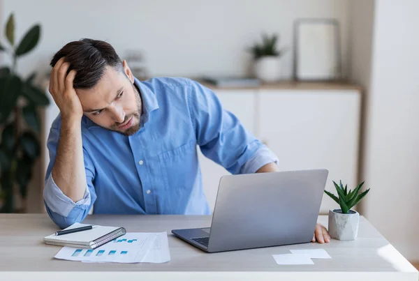 Stressvolle, vermoeide zakenman die problemen heeft op het werk, zit achter een bureau met laptop — Stockfoto