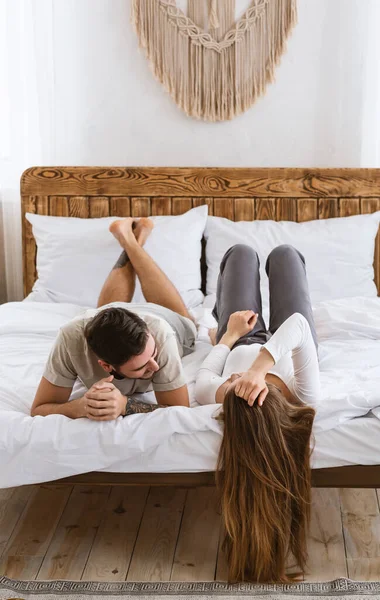 Comunicazione familiare e relazioni romantiche. Giovane marito e moglie sono sdraiati sul letto, guardando l'un l'altro — Foto Stock