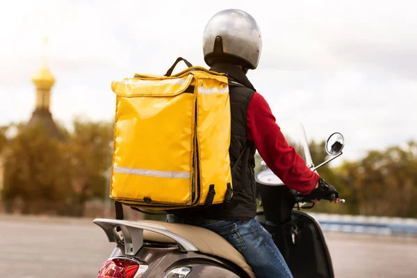Kurier mit gelbem Rucksack, der Mahlzeiten auf dem Motorroller nach draußen liefert, Rückansicht — Stockfoto