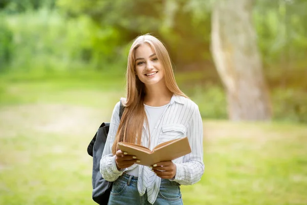 Portret uśmiechniętej studentki uniwersytetu pozowanie na zewnątrz w kampusie, Holding Book — Zdjęcie stockowe