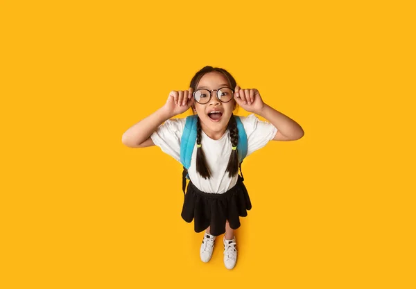 Rolig asiatisk skolflicka bär glasögon leende Posing över gul bakgrund — Stockfoto