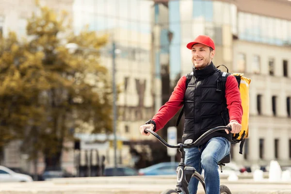 Joyful Courier Man andar de bicicleta entregando refeições na área urbana — Fotografia de Stock